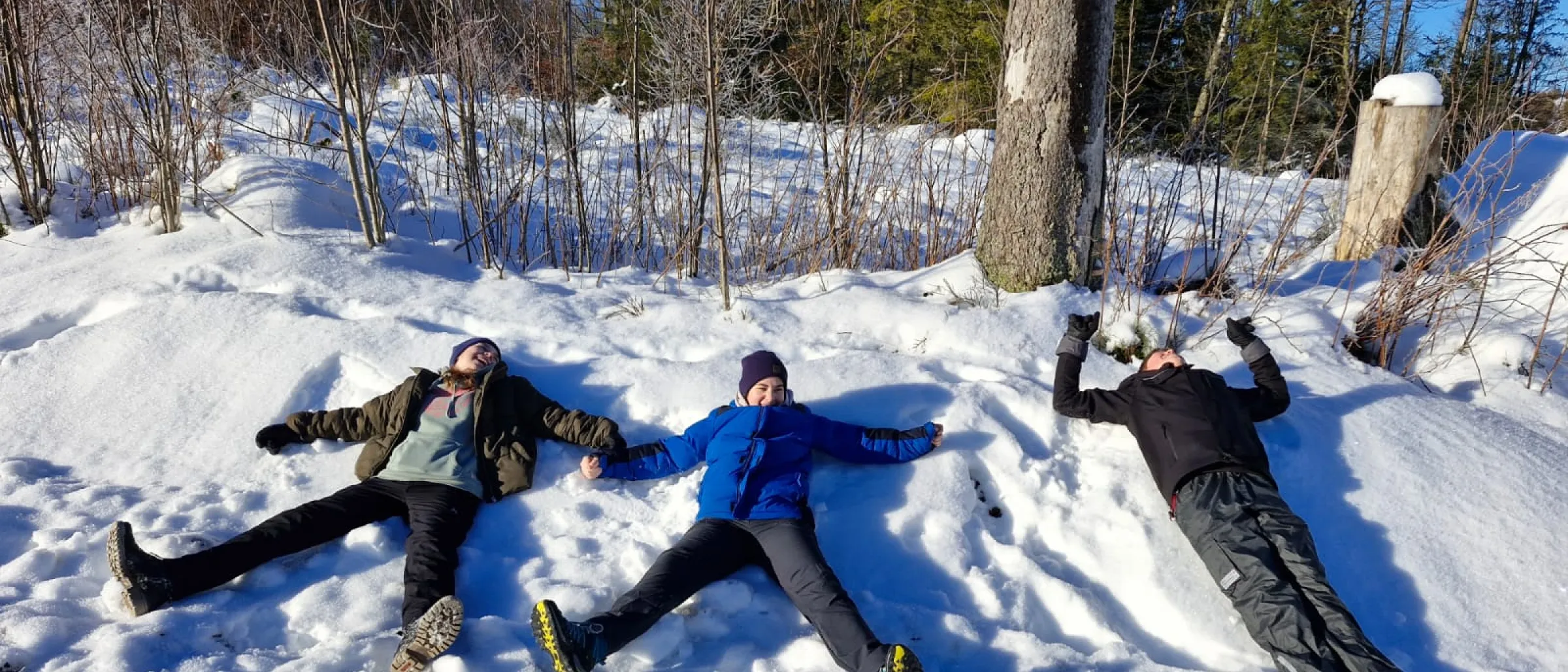 drei Konfis liegen im Schnee